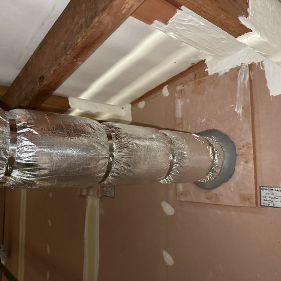 Insulated steel pipe penetration sealed with fire-rated mastic and Halt Fire compliance tag