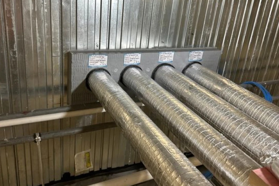 The same insulated copper pipes fire stopped through the KOROK panel wall with a fire batt, mastic and graphite strap, tagged by Halt Fire