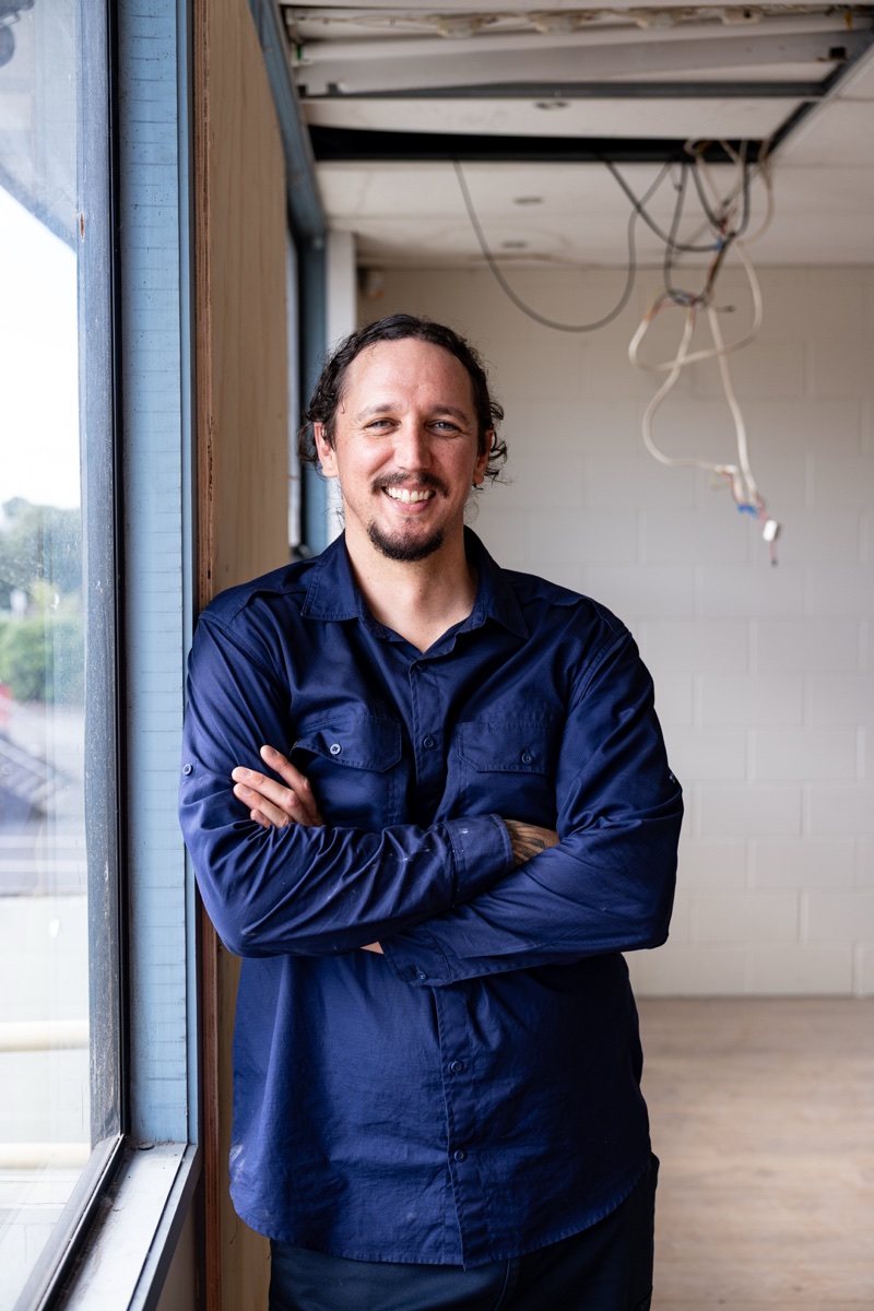 Damyn Blindell, Managing Director of Halt Fire, in a blue work shirt with arms crossed on a building site
