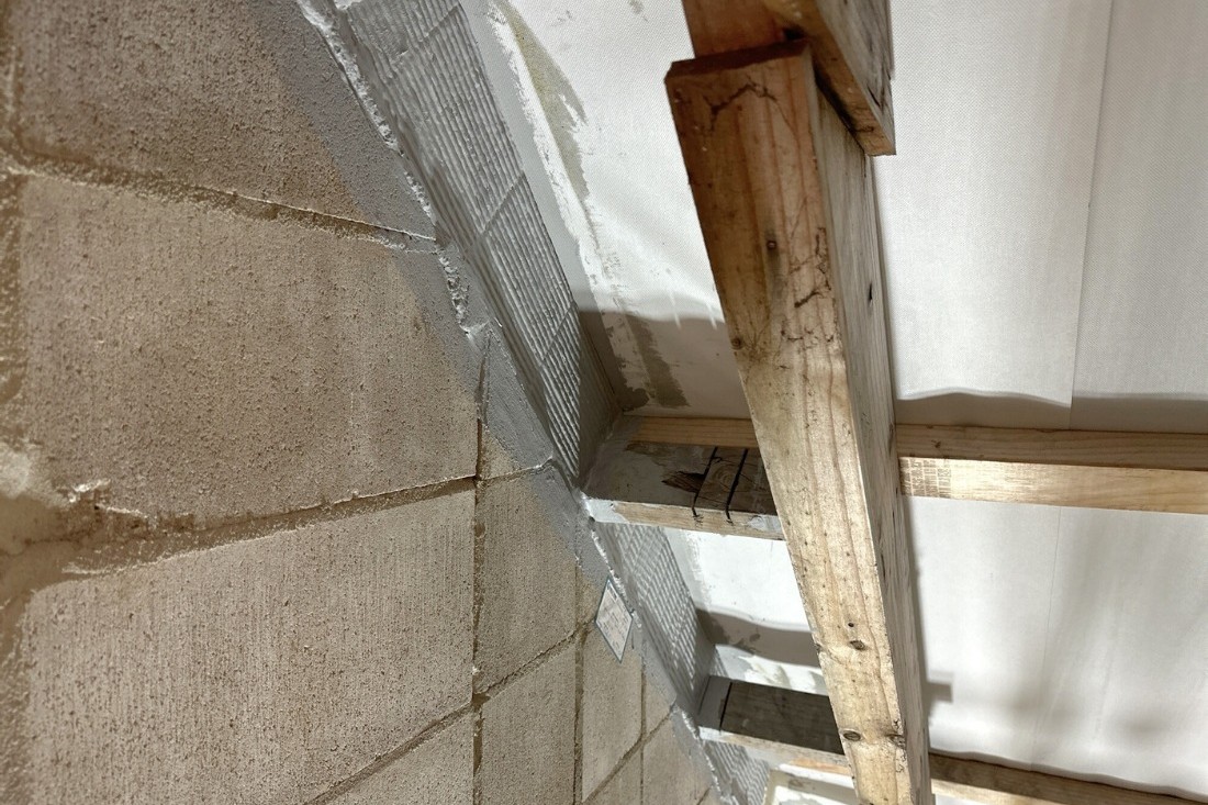 Head-of-wall gap in a fire-rated block wall sealed with a tested batt and mastic system